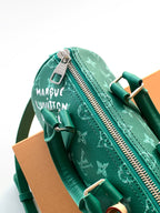 Louis Vuitton green monogram bag showing zip pull and brand patch tag