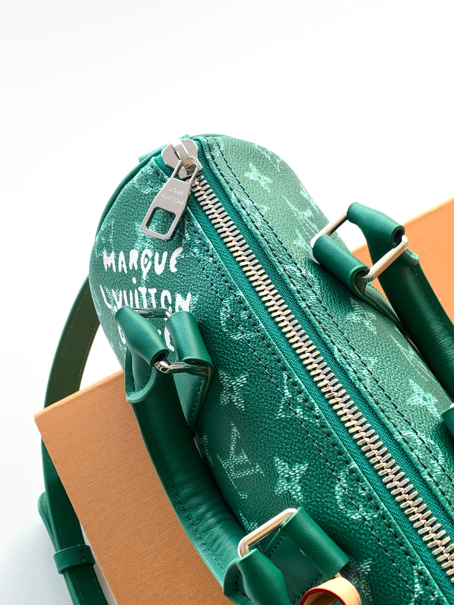 Louis Vuitton green monogram bag showing zip pull and brand patch tag