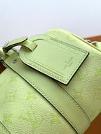 Louis Vuitton green leather bag close-up with stitched strap and flap pocket