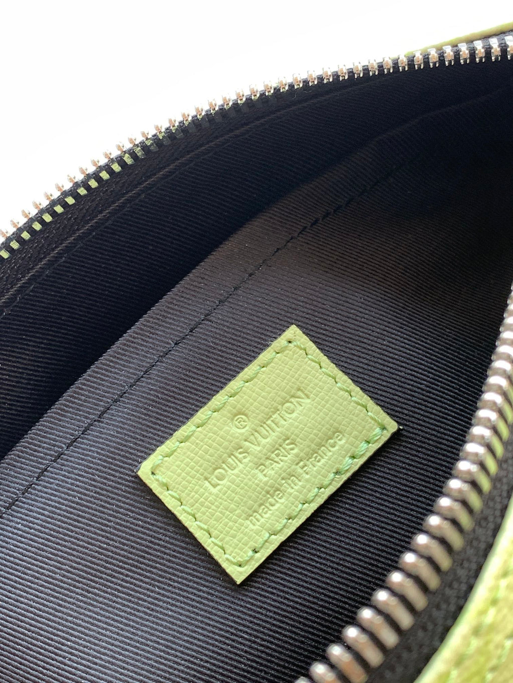 Louis Vuitton green logo patch on black fabric lining inside the bag