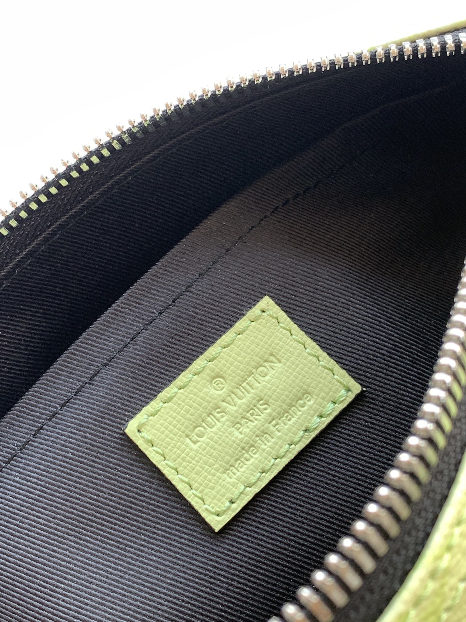 Louis Vuitton green logo patch on black fabric lining inside the bag