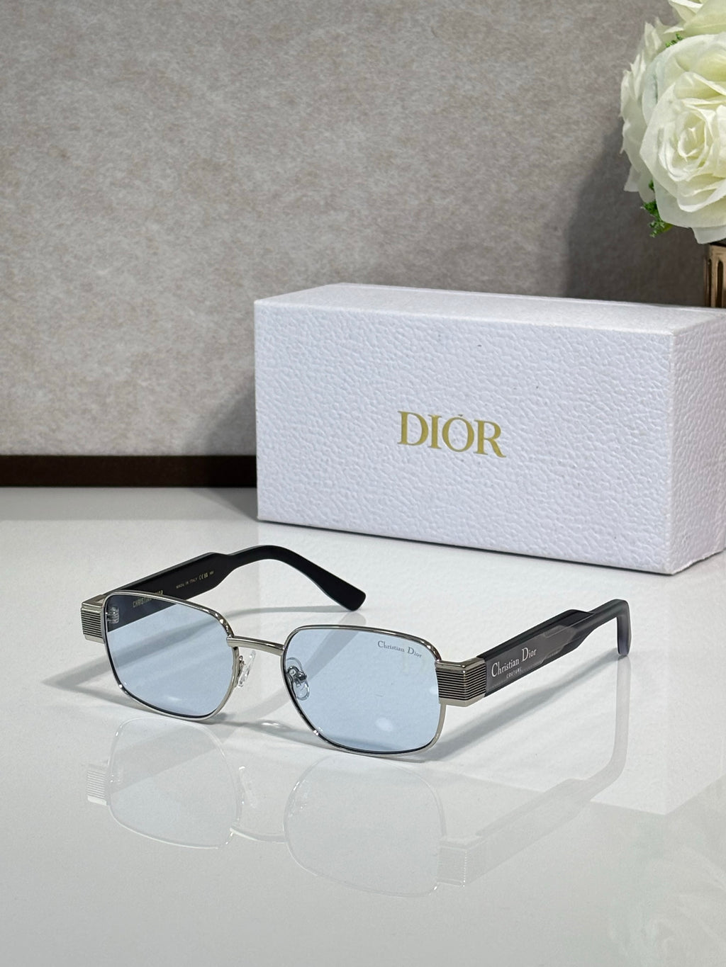 Sunglasses with silver frame and light blue lenses, black temple tips