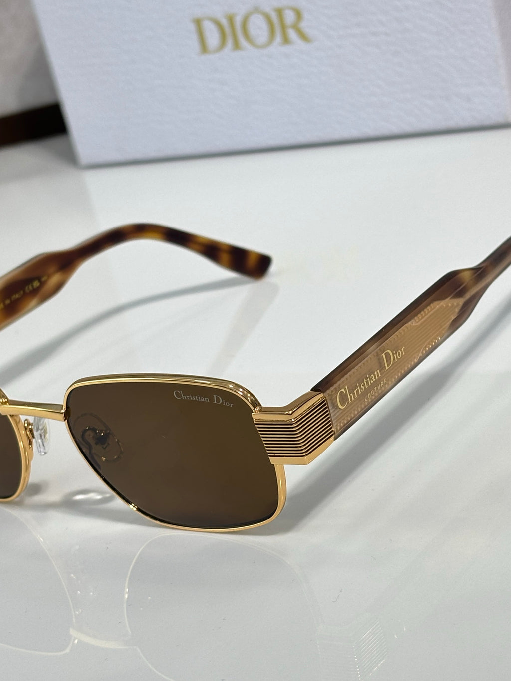 Sunglasses close-up with tortoise frame, brown lenses, gold temple stripes