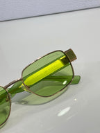 Sunglasses close-up with green lenses and gold-tone temple detail