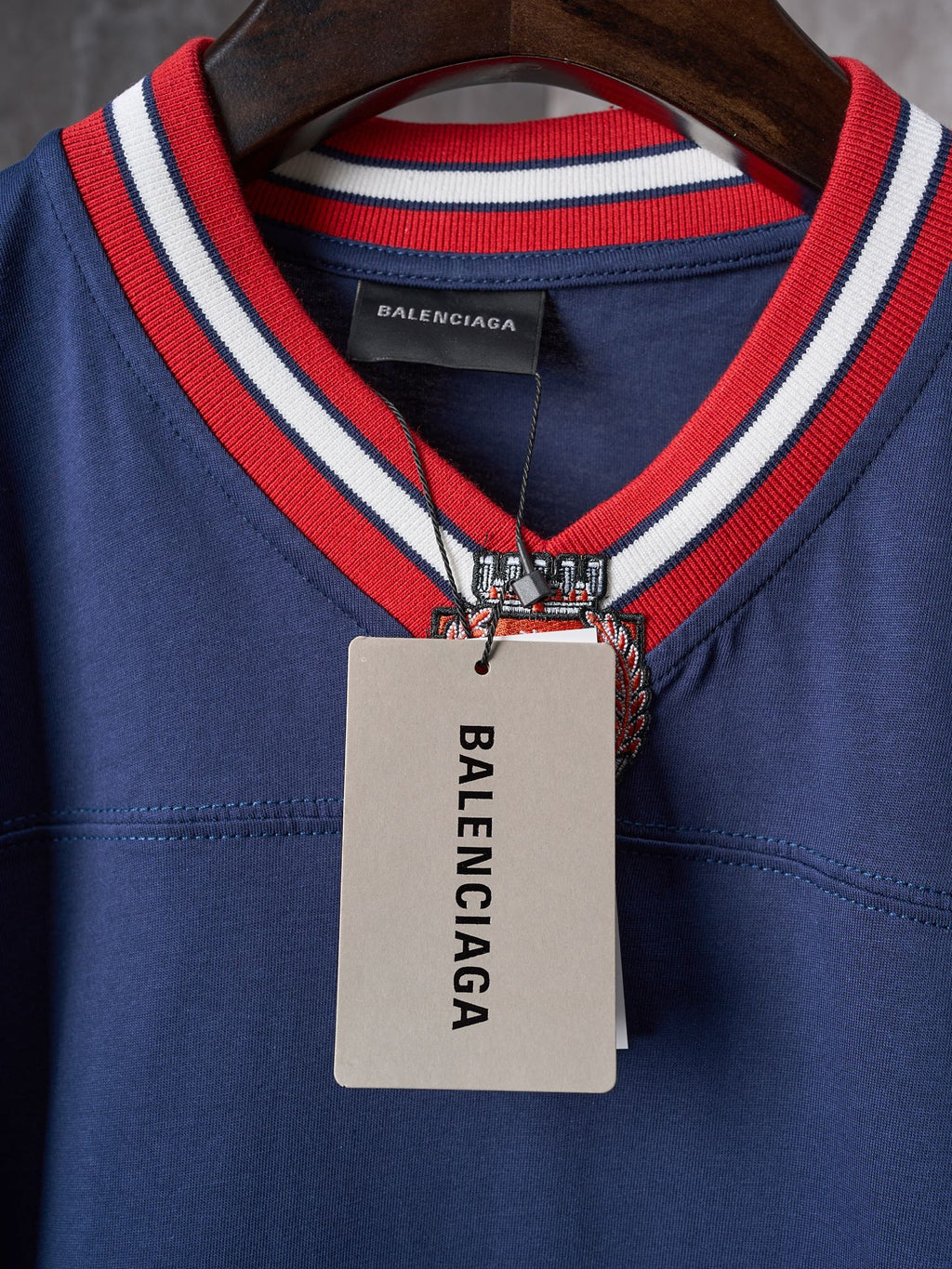 Balenciaga navy jersey with crest emblem, inner neck label, and hanging tag