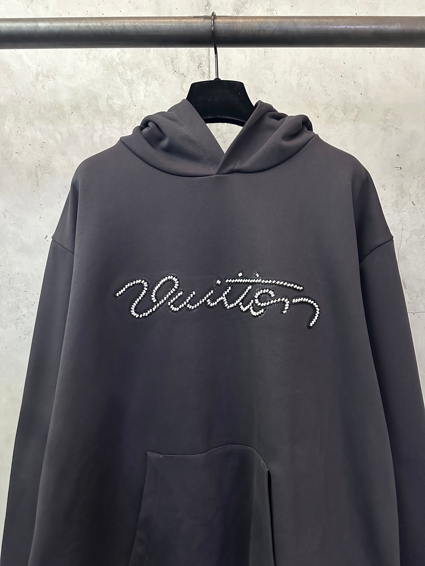 Black long-sleeve hoodie with rhinestone script logo, front close-up and kangaroo pocket