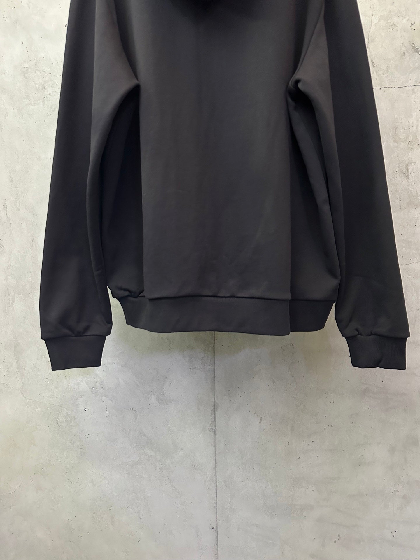 Black long-sleeve hoodie with hood and cuffs, back view
