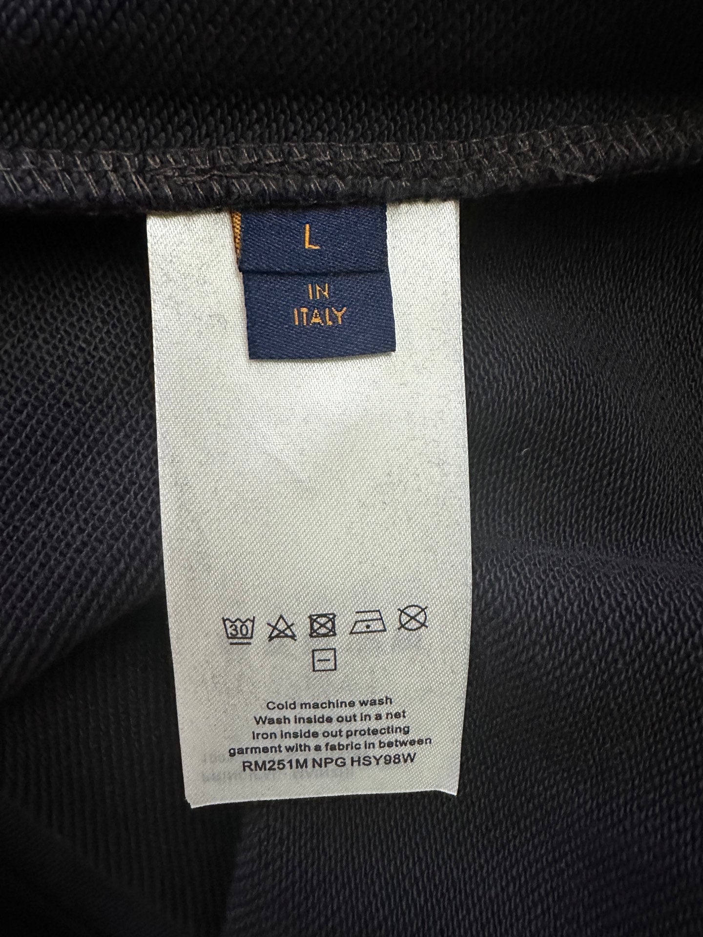 Clothing care label on black hoodie, size L, Italy