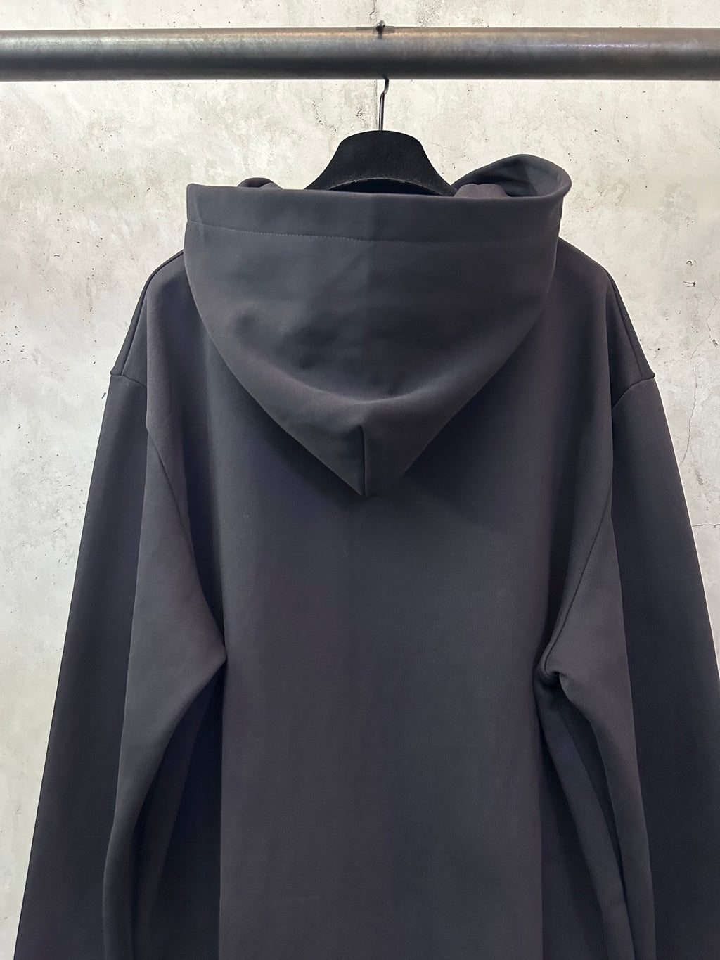 Black long-sleeve hoodie with hood and relaxed sleeves, back view