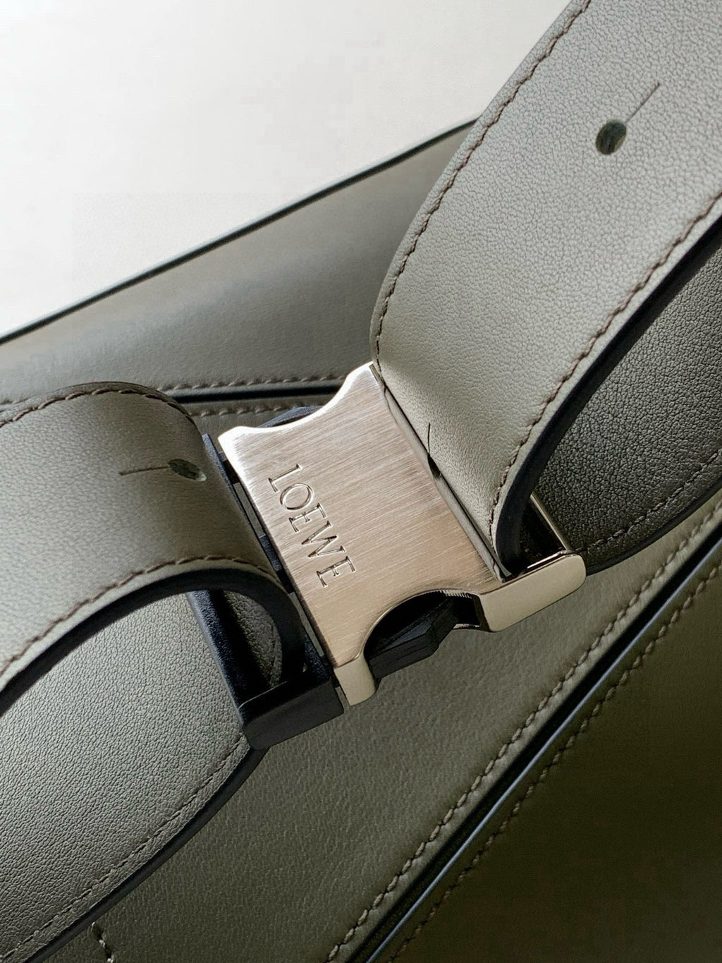 Loewe leather bag strap detail with gold-toned buckle and debossed logo plate