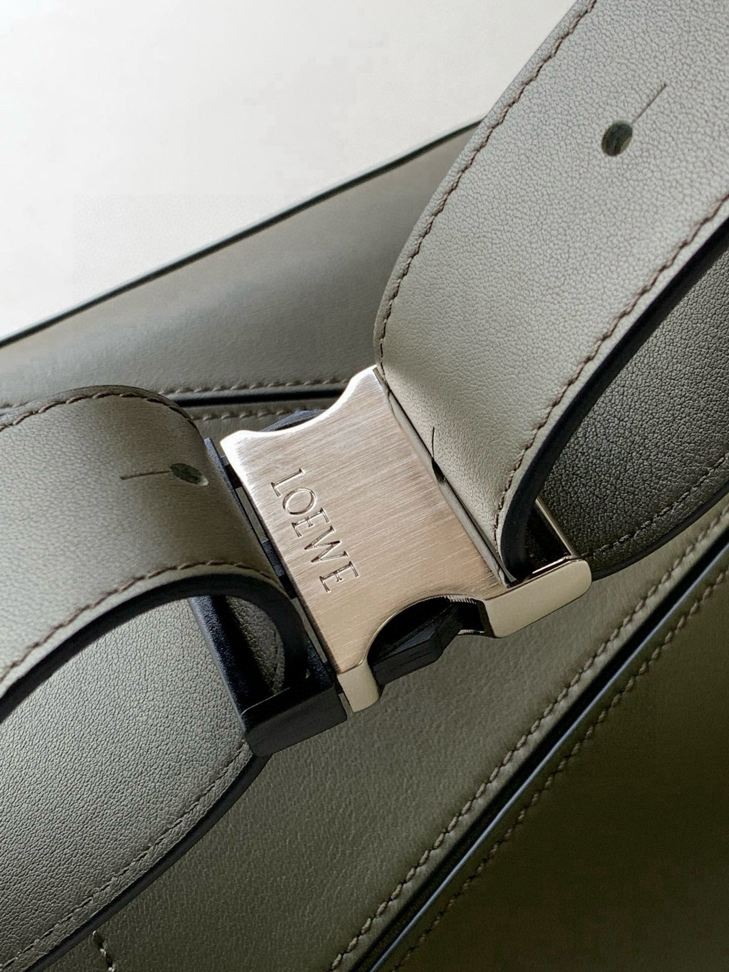 Loewe leather bag strap detail with gold-toned buckle and debossed logo plate