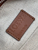 Loewe bag brand patch label in dark brown on light herringbone fabric