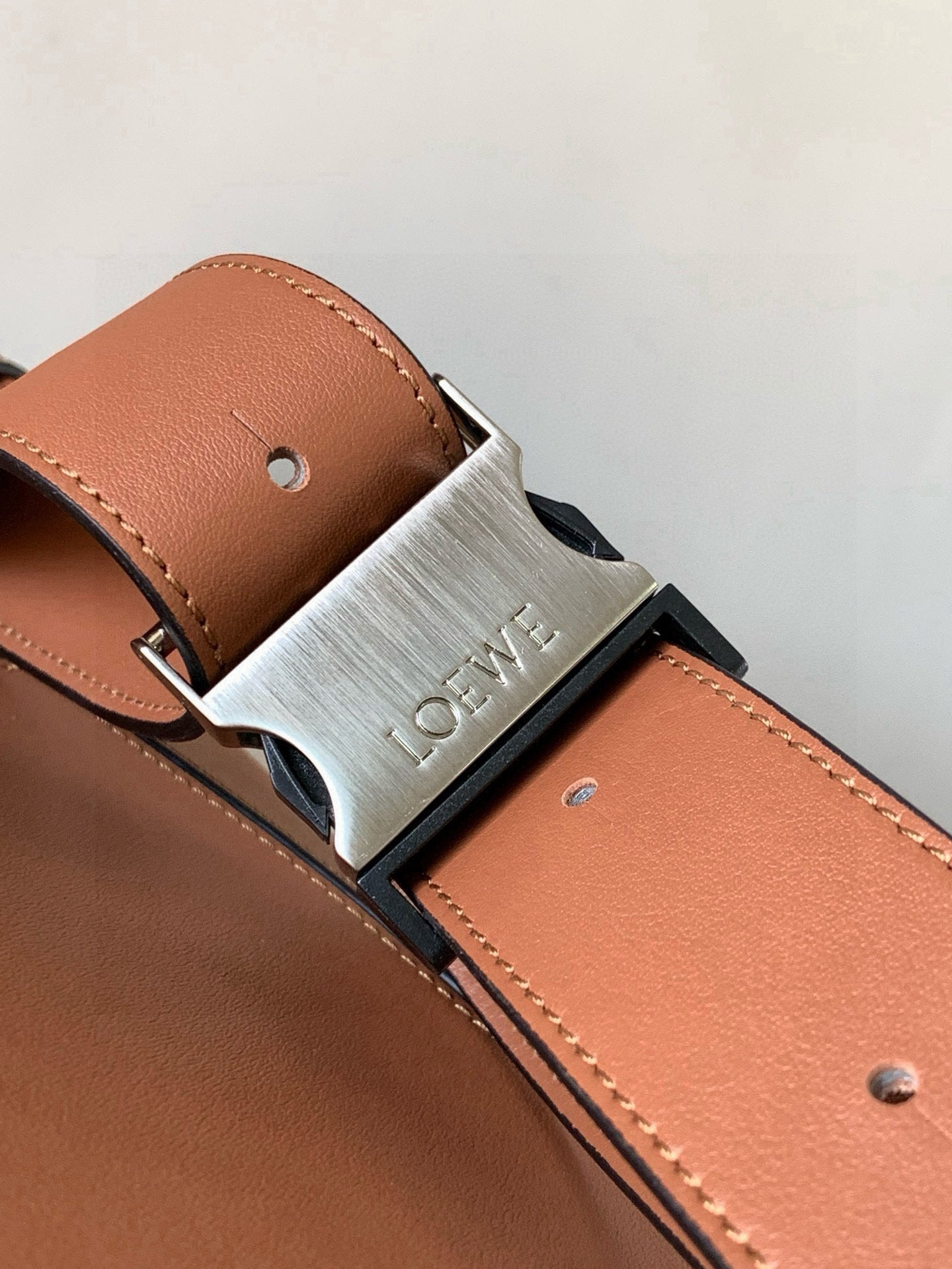 Loewe bag strap hardware with engraved metal buckle on peach leather