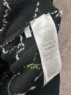 Black knit sweater tag with Gucci label, stitched abstract pattern
