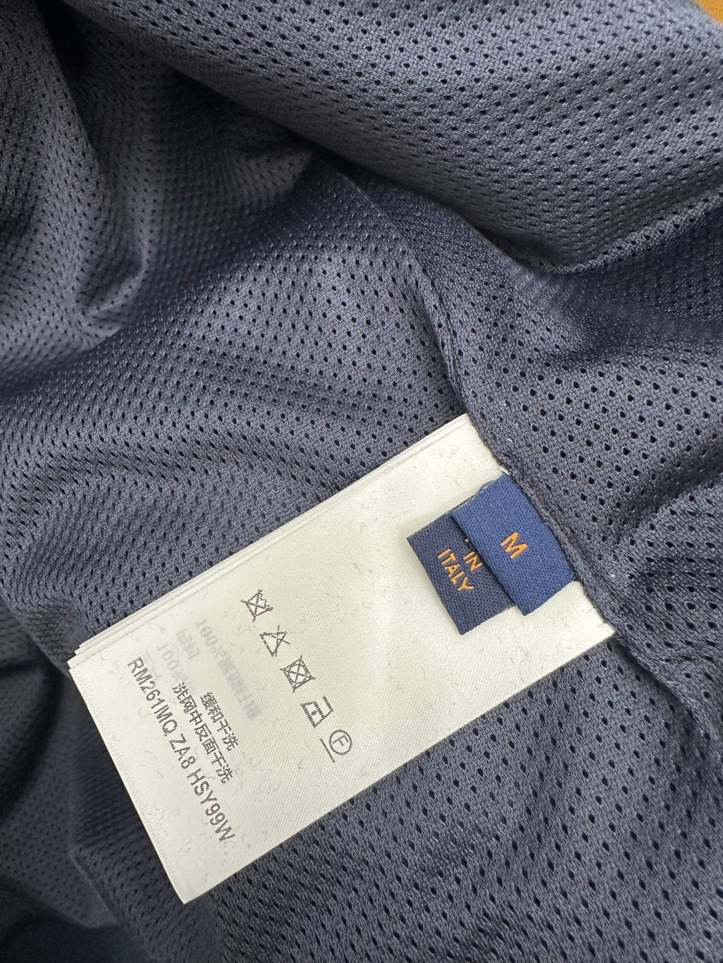 Louis Vuitton fabric label on dark blue long-sleeve jacket, close-up