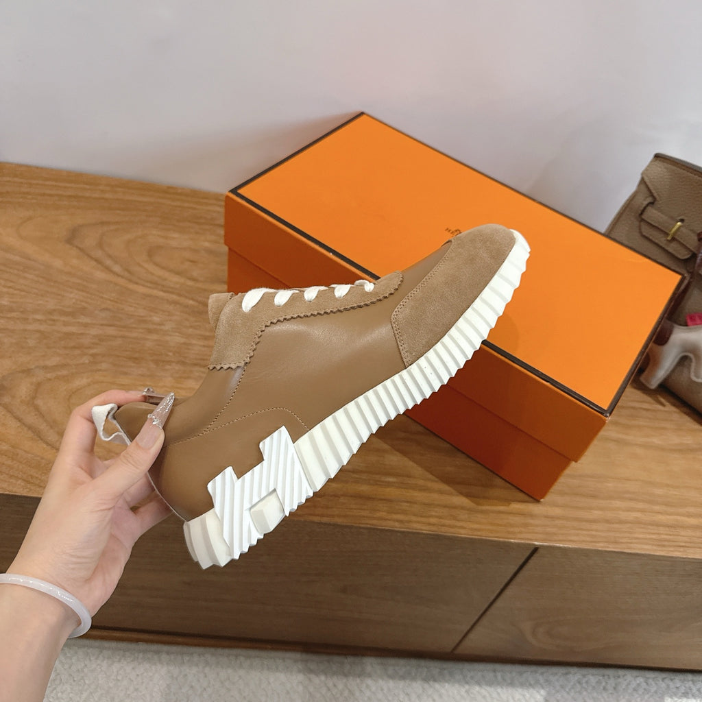 Tan suede sneaker being held, with white ridged sole and white stitched detailing