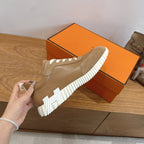 Tan suede sneaker being held, with white ridged sole and white stitched detailing