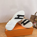 Shoe outsole view: white ridged sole with black stripe details on tan upper