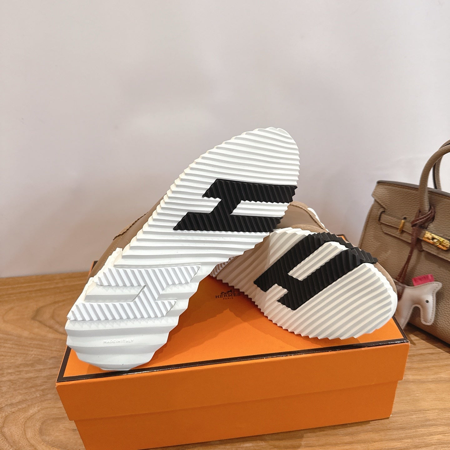 Shoe outsole view: white ridged sole with black stripe details on tan upper