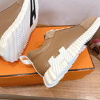 Tan sneaker close-up on box with white laces and chunky white ridged sole