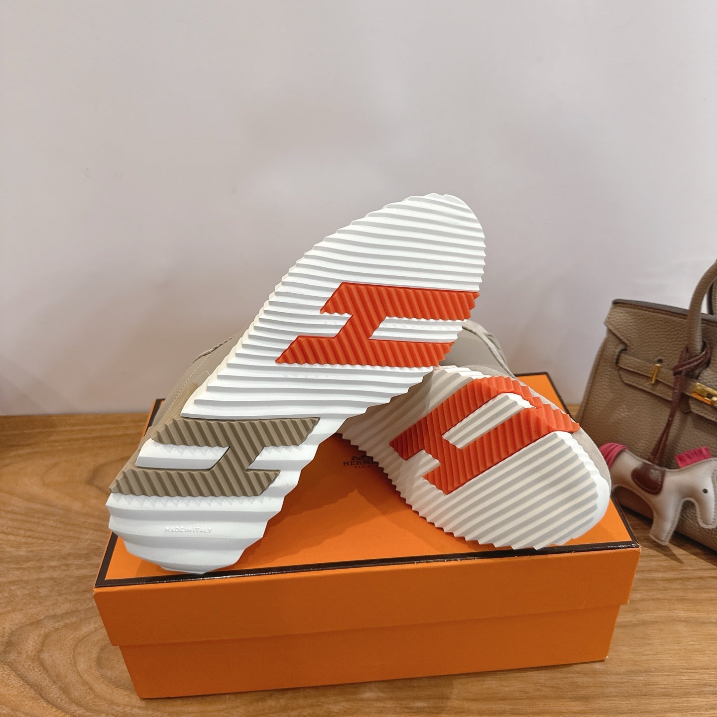 Beige sneaker outsole with striped tread and orange box base
