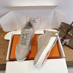 Pair of beige lace-up sneakers with white striped sole in open box