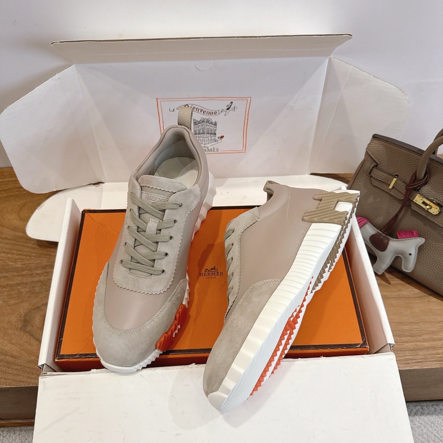 Pair of beige lace-up sneakers with white striped sole in open box