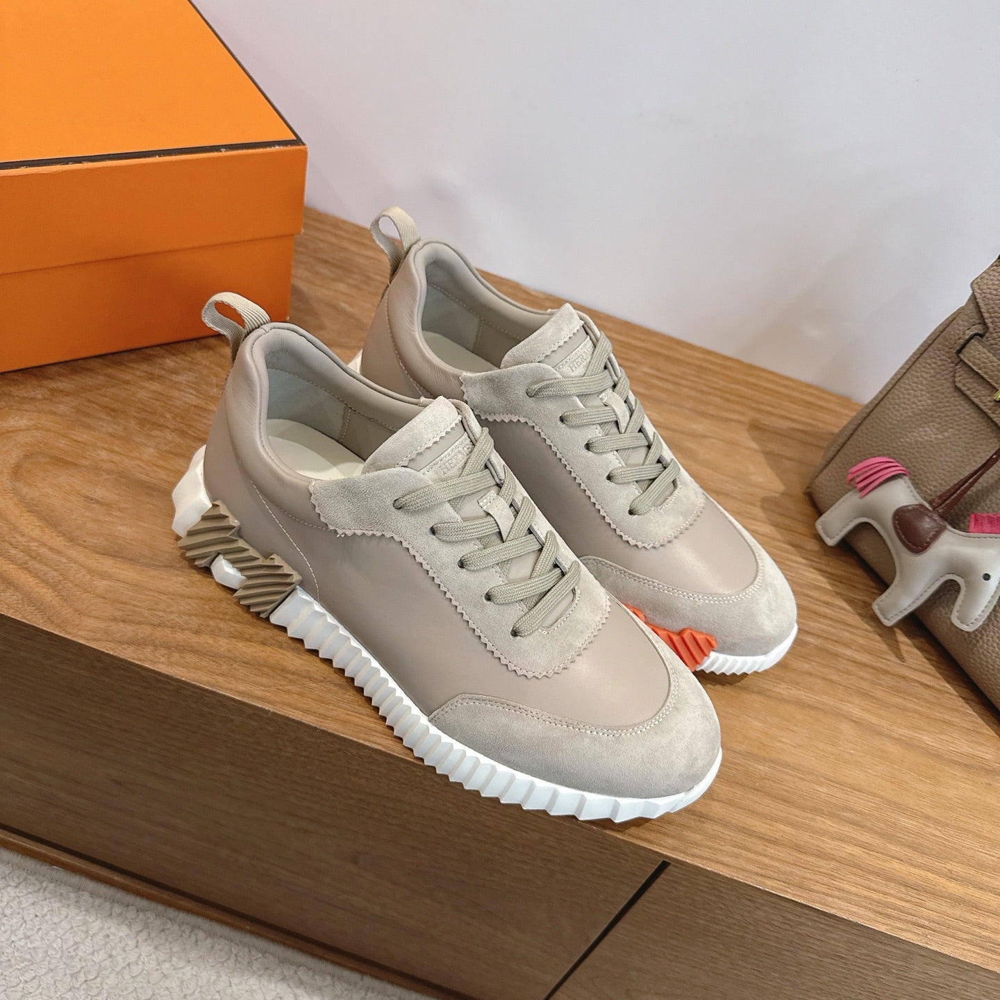 Beige lace-up sneakers with white ribbed sole, placed on a wooden surface