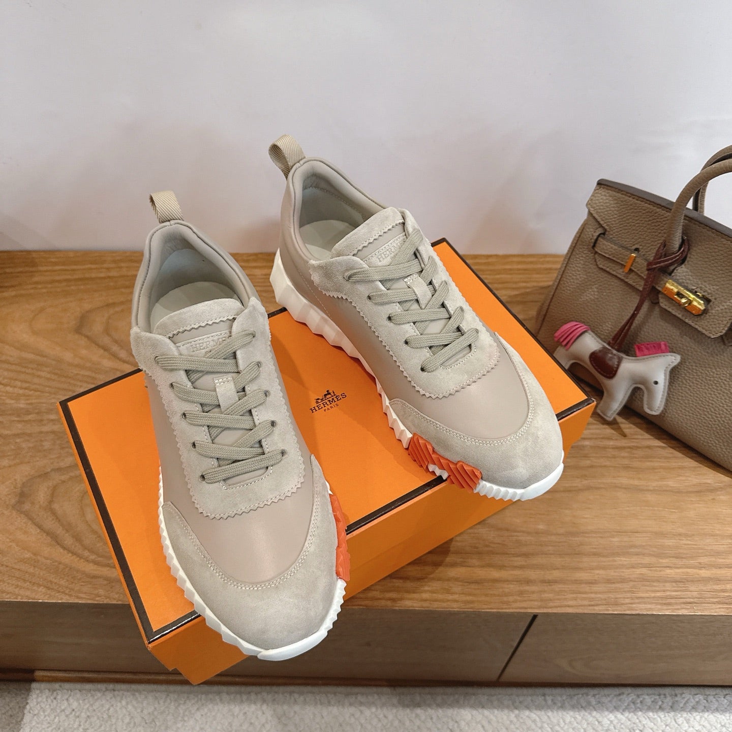 Beige lace-up sneakers on an orange shoebox lid with white rubber sole