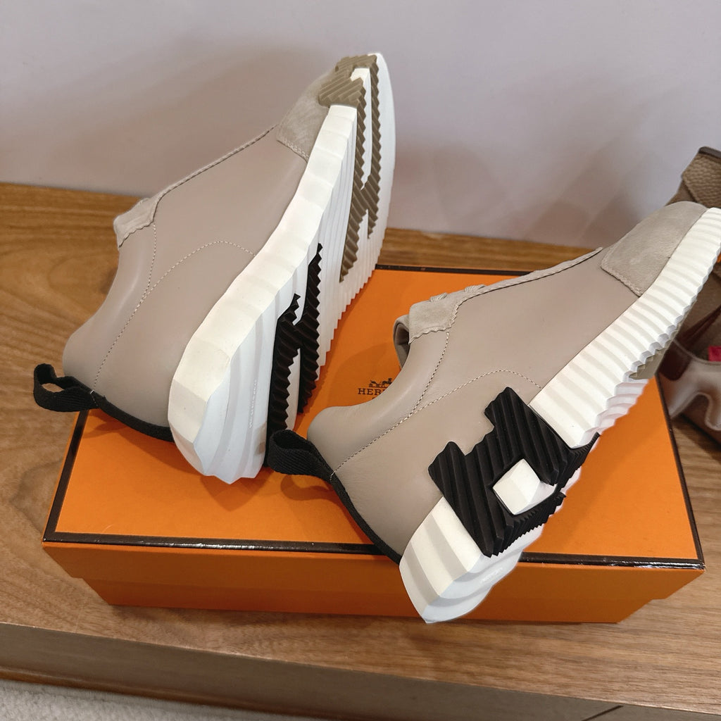 Unisex sneakers side view on orange box, light beige upper with black logo