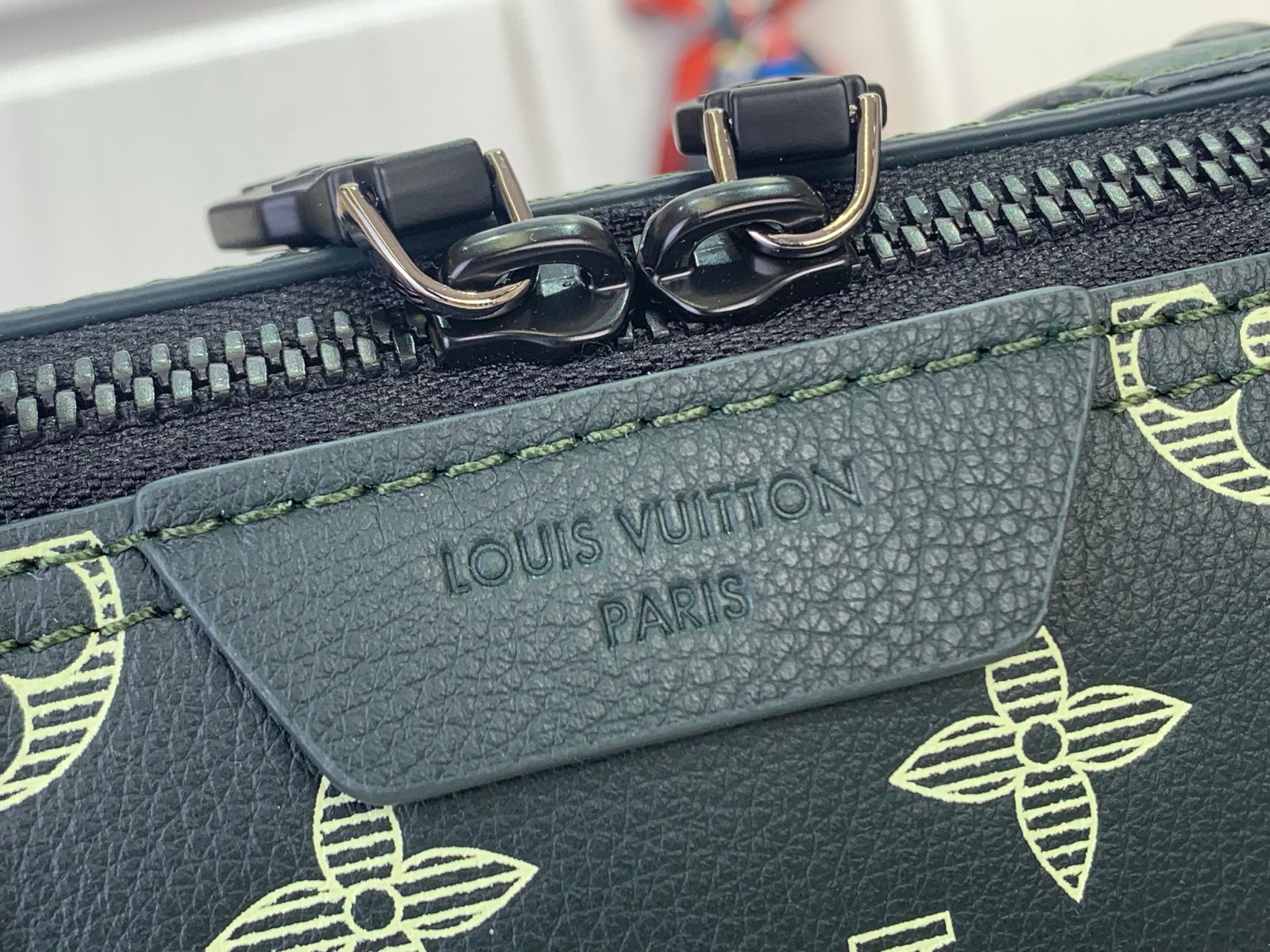 Louis Vuitton leather label reading “LOUIS VUITTON PARIS” near zipper teeth