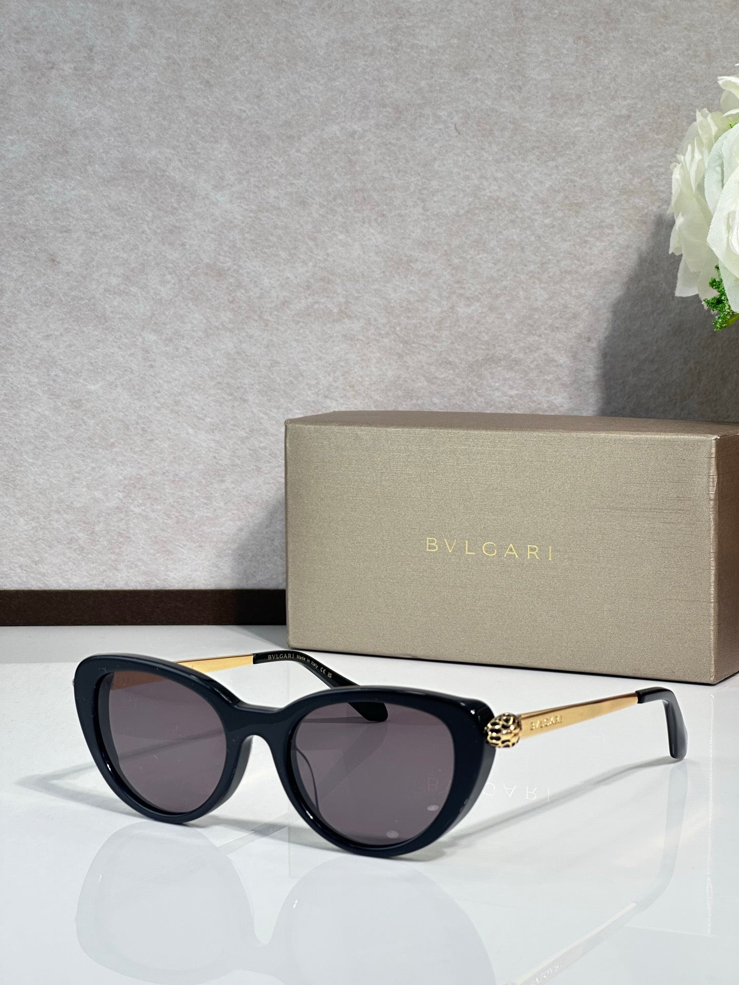 Bvlgari sunglasses with black rounded frames and dark lenses, gold-tone temple detail