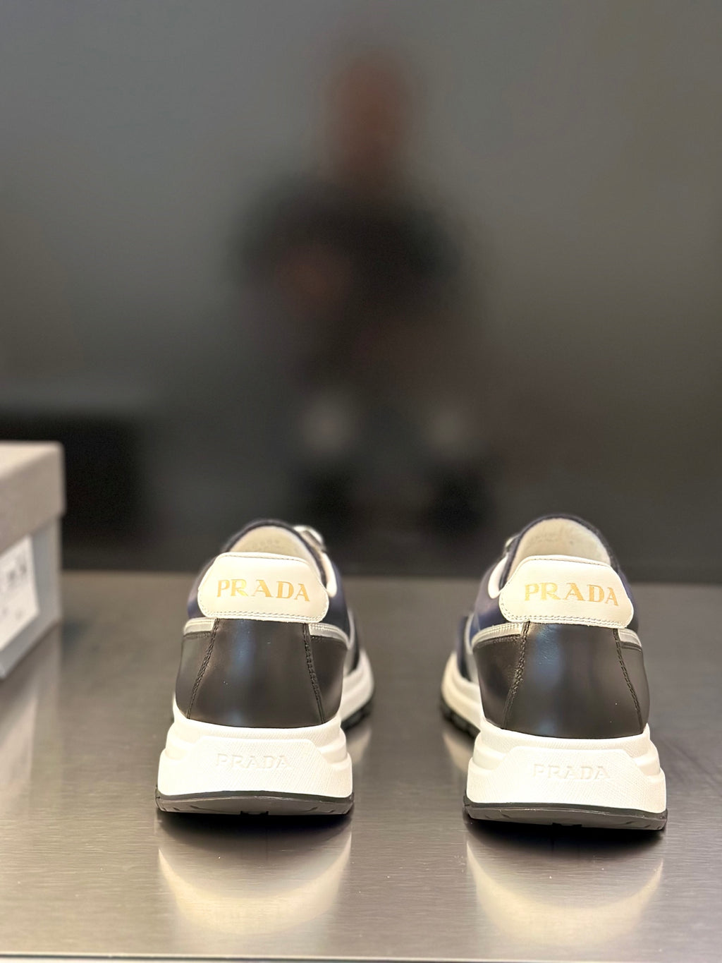 Prada unisex sneakers, rear view with PRADA logo on heel, dark navy