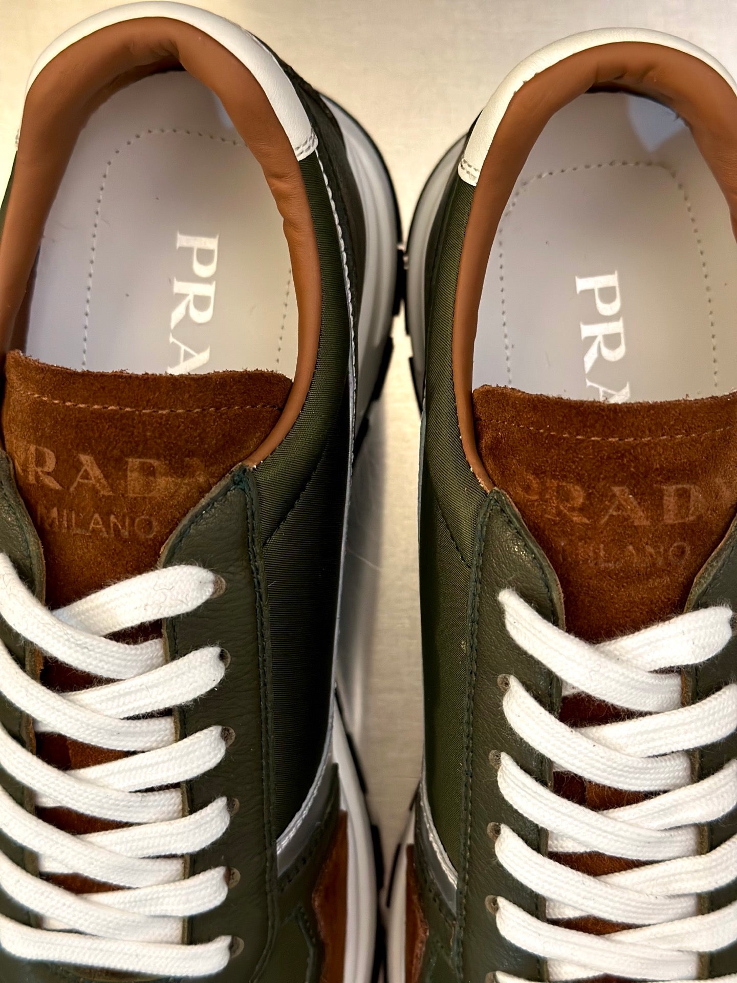 Prada unisex sneakers close-up: PRADA on white insole, brown lining, white laces