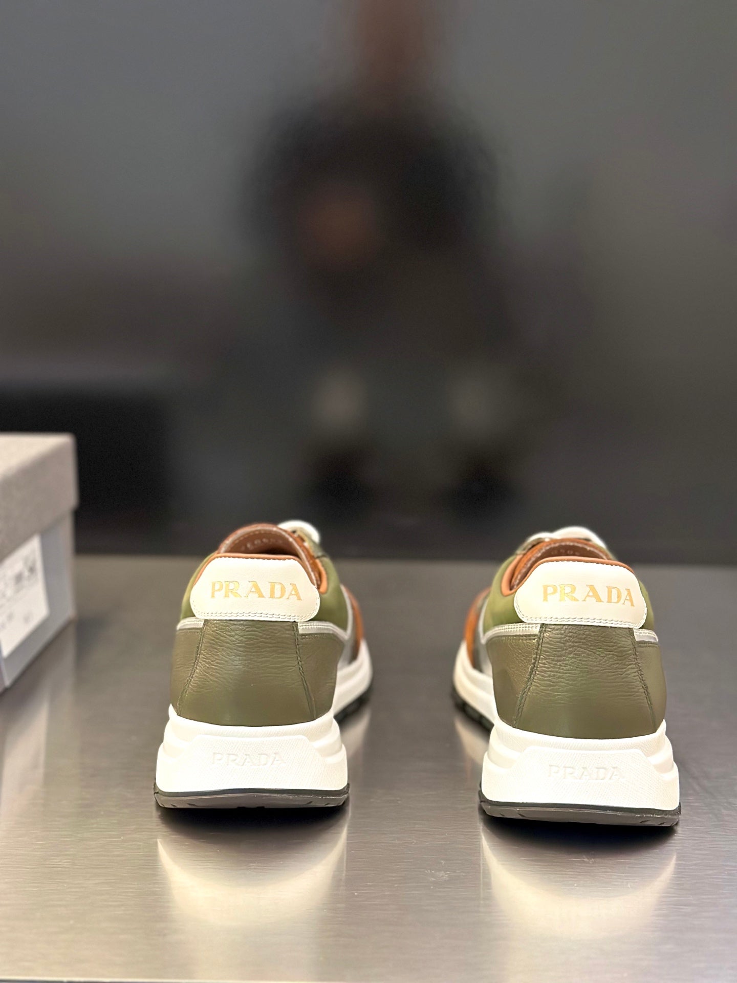 Prada unisex sneakers rear view with PRADA on heel tabs; olive green and white sole