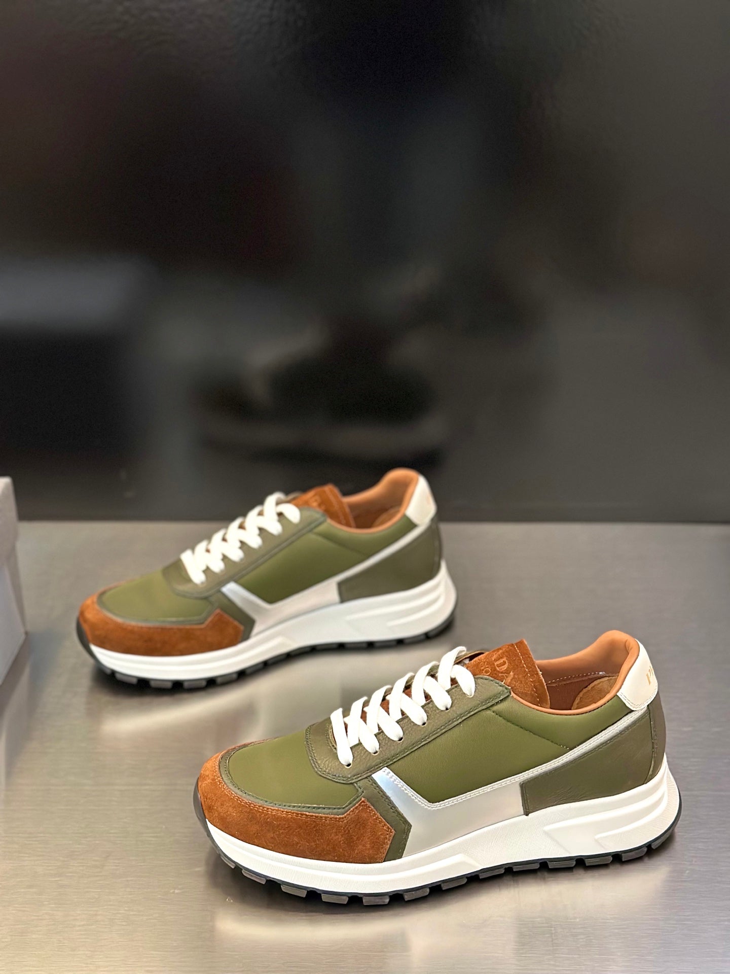Prada unisex sneakers, two-quarter view; olive green, brown details, white laces
