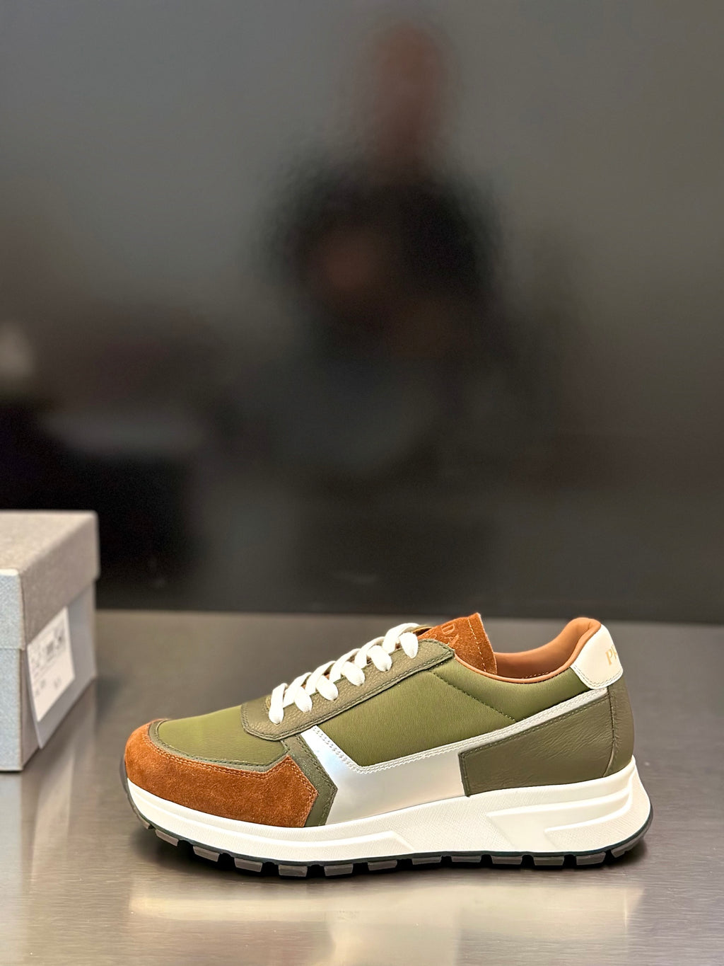 Prada unisex sneakers in olive green with brown panels and white laces, side profile