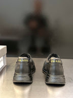 Prada unisex lace-up sneakers, dark gray; rear view with PRADA branding on heel