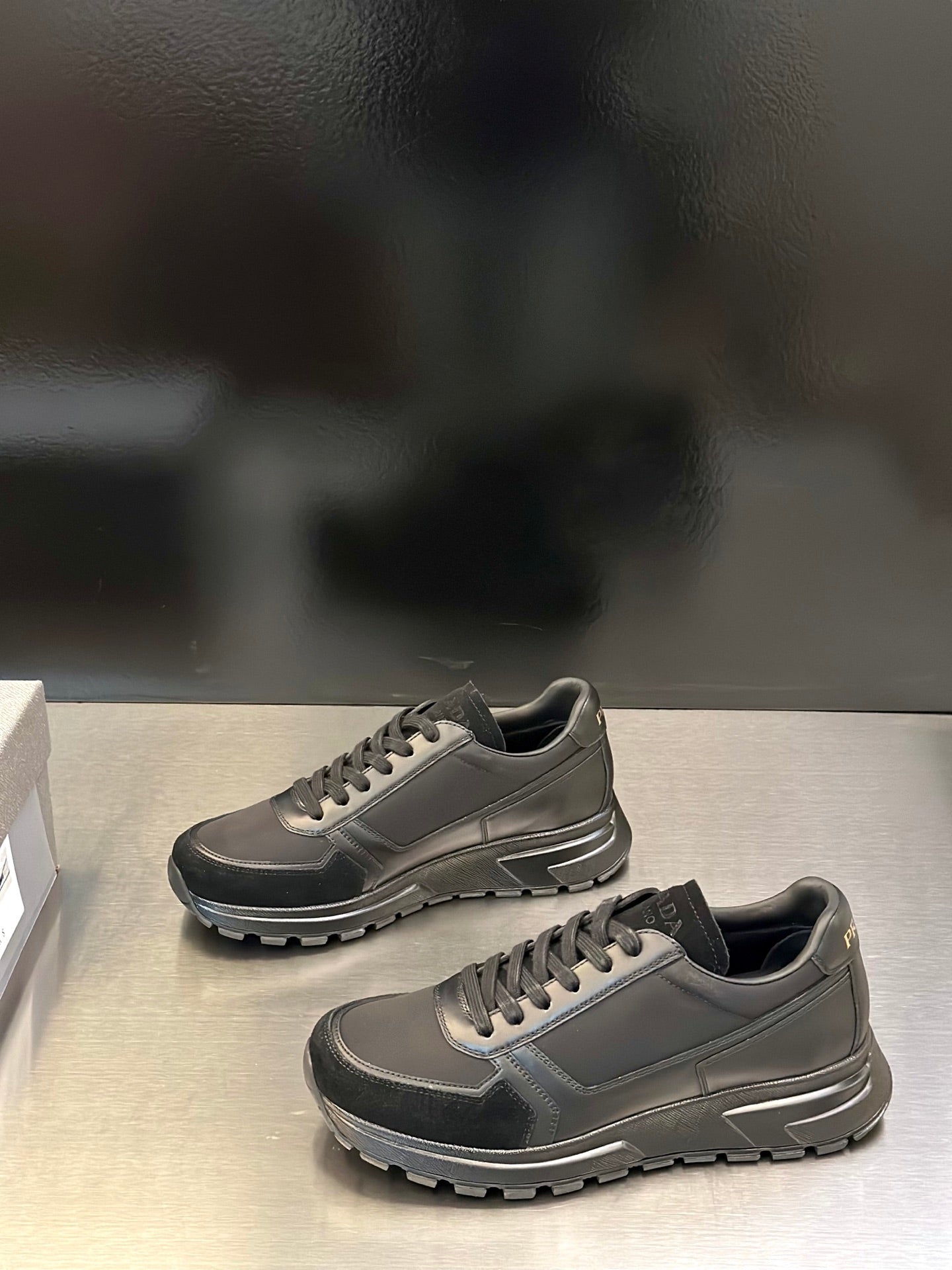 Prada unisex lace-up sneakers, gray with dark accents; side-by-side view and tread sole