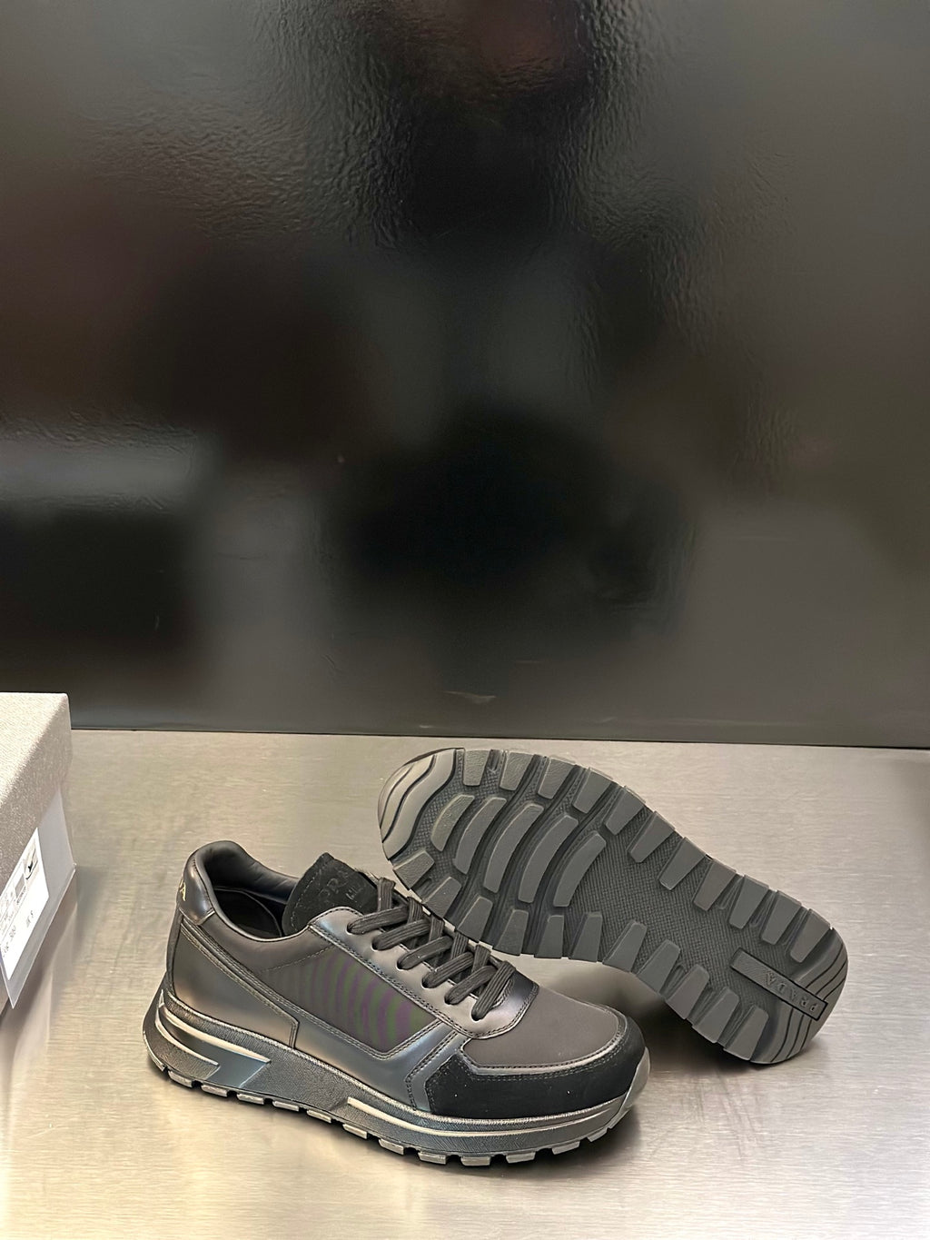 Prada unisex lace-up sneakers, metallic gray with black toe and visible tread outsole