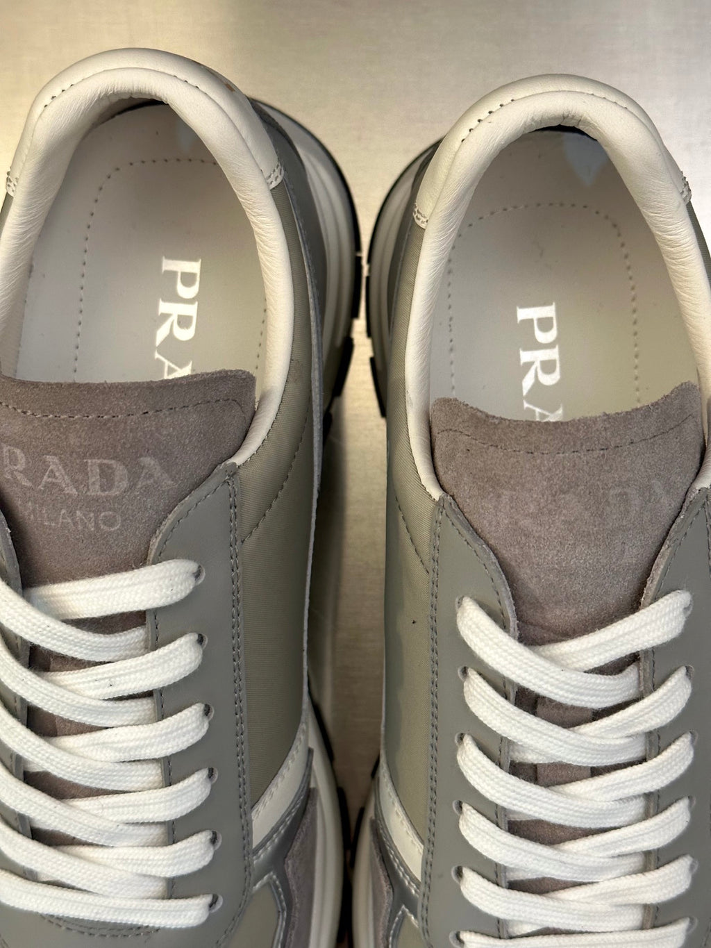 Close-up of Prada unisex sneaker tongues and side panels with white laces