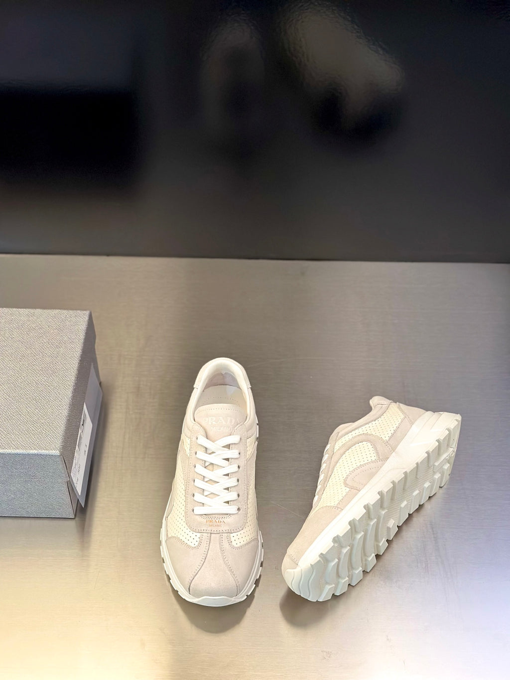 Prada unisex sneakers with one shoe side view; light off-white lace-up upper