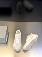 Prada unisex sneakers with one shoe side view; light off-white lace-up upper