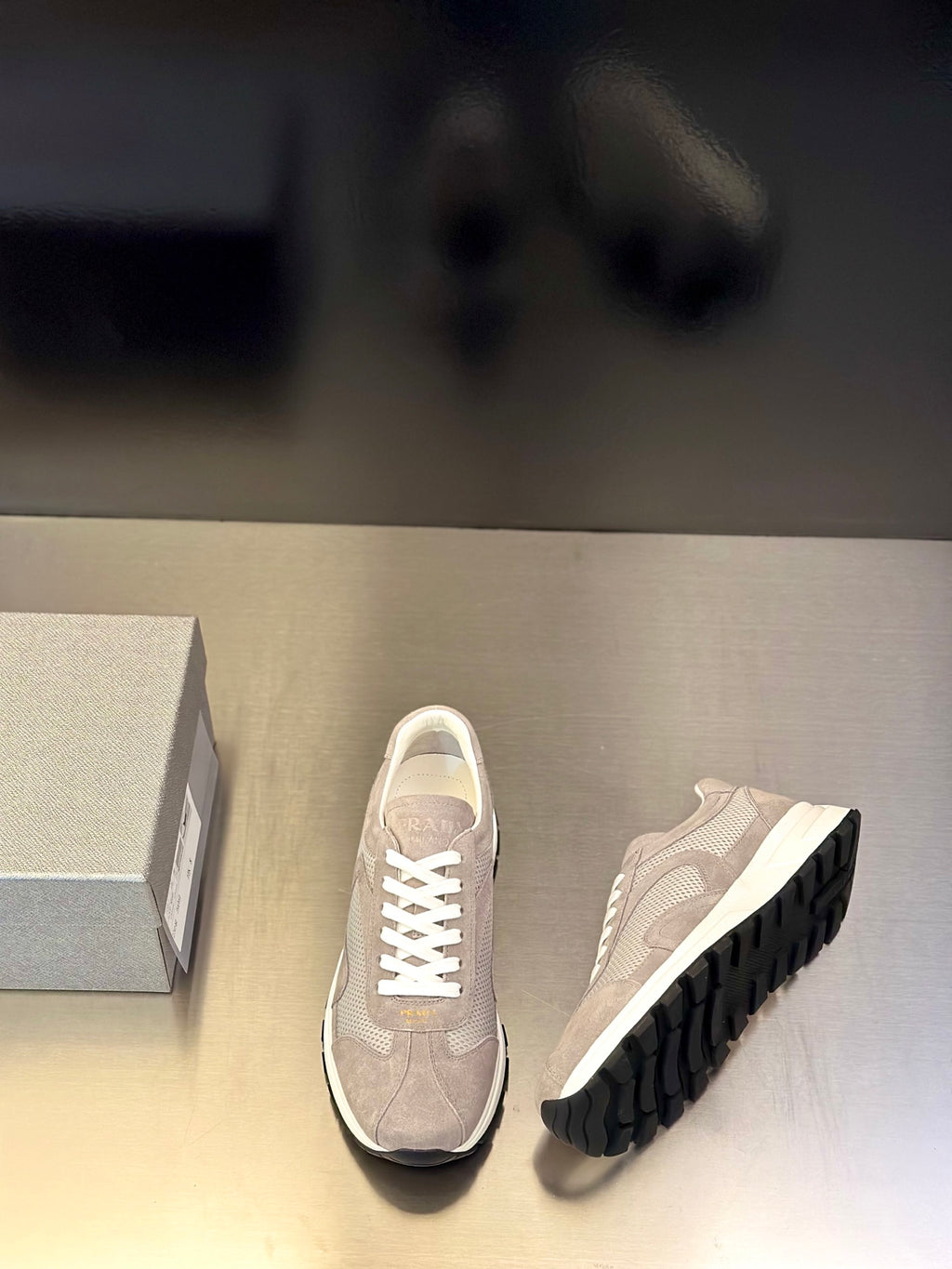 Prada unisex sneakers, light gray front and side view, white laces, dark tread outsole