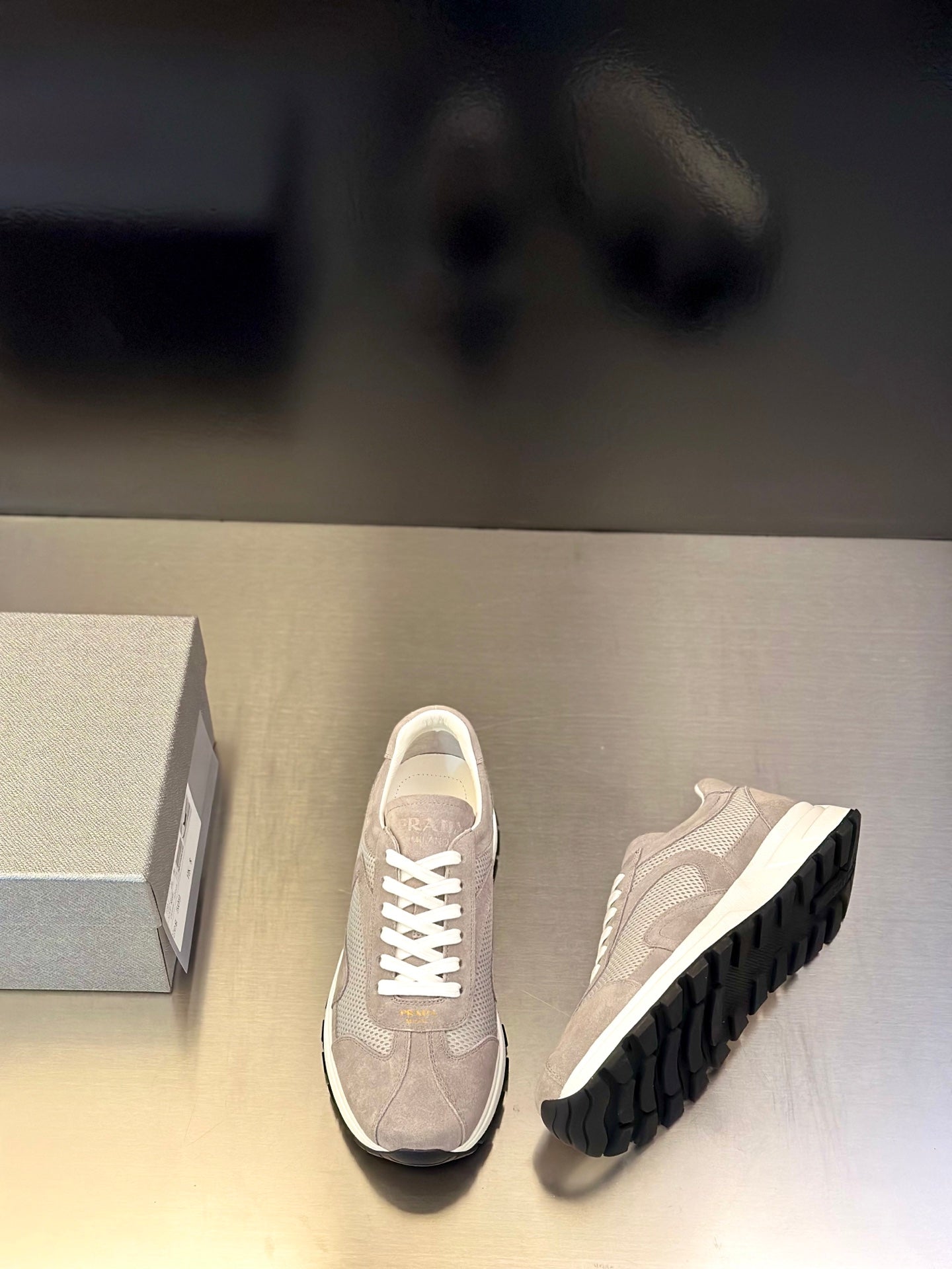 Prada unisex sneakers, light gray front and side view, white laces, dark tread outsole