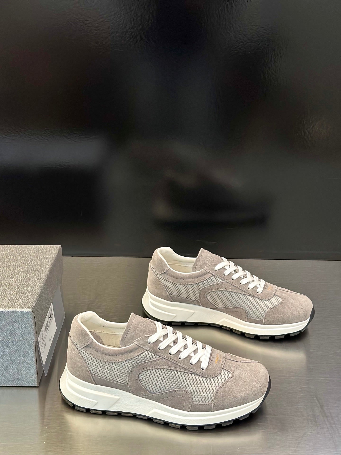 Prada unisex sneakers with light gray upper, white laces, thick black-rim sole