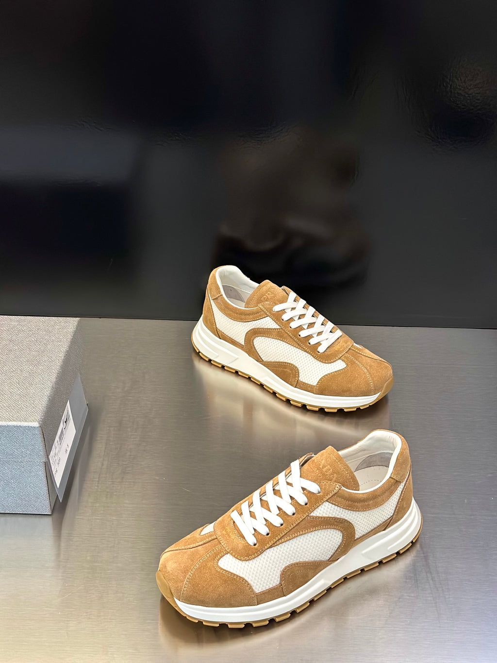 Tan suede lace-up sneakers with white swoosh-style panels and rubber sole
