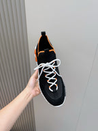 Hermes unisex sneakers close-up, black fabric with orange lining, white laces and midsole