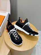 Hermes unisex sneakers pair, black with orange accents, white laces, chunky white sole