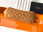 Quilted tan handbag with top handle and folded flap detail, diamond stitching